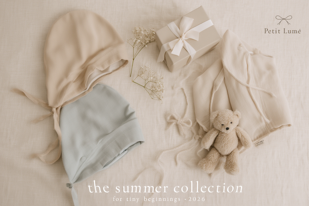 Petit Lu flat lay with layette pieces, bow ribbon gift box, and keepsake teddy